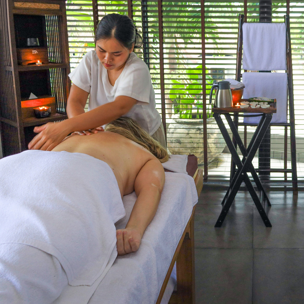 a skilled and certified therapist is performing an oil massage on a customer who is lying with her face down on a massage bed in a massage room in Amla Aqua - Organic spa & hydrotherapy in Cherngtalay, Phuket